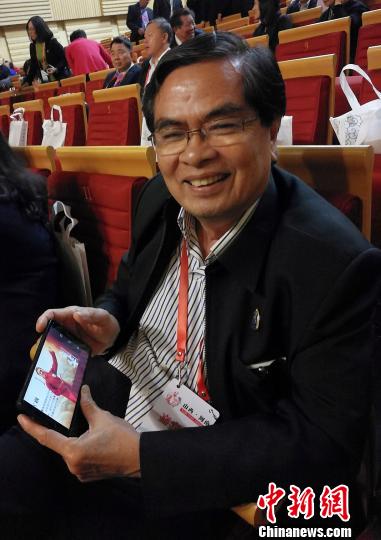 泰国华文民校协会中文秘书、泰国明满学校校长陈松向记者展示学生参加“汉语桥”比赛的照片。　杨杰英 摄