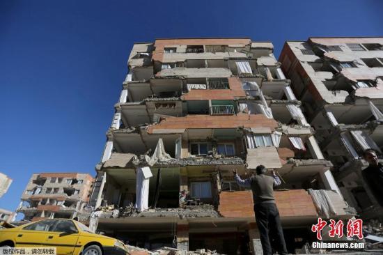 当地时间11月12日晚间发生在伊朗和伊拉克边界地区的7级以上强震，已造成至少348人遇难，超过5000多人受伤，70000人因地震无家可归。据悉，此次强震后，大约发生了50次余震。地震在伊朗多地引起恐慌，居民连夜跑到街上避难，围着篝火在户外过夜。与此同时，伊朗当局也向受灾地区提供援助。伊朗救援人员13日继续在废墟中搜寻幸存者。不过，地震还引发山体滑坡，影响救援人员接近灾区。图为伊朗克尔曼沙赫县的一栋建筑严重损毁。