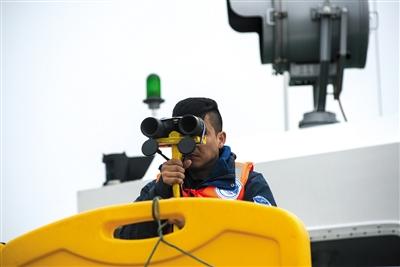 科考船上，目视观察员通过望远镜观测是否出现江豚。