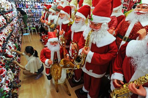 资料图片：浙江义乌国际商贸城的两位经营户在为采购商准备圣诞老人样品(2015年7月19日摄)。新华社记者 谭进 摄