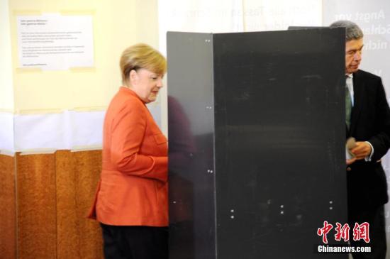 当地时间9月24日下午，德国总理默克尔在柏林洪堡大学的投票站参加大选投票。图为默克尔和丈夫绍尔在写票。<a target='_blank' href='http://www.chinanews.com/'>中新社</a>记者 彭大伟 摄