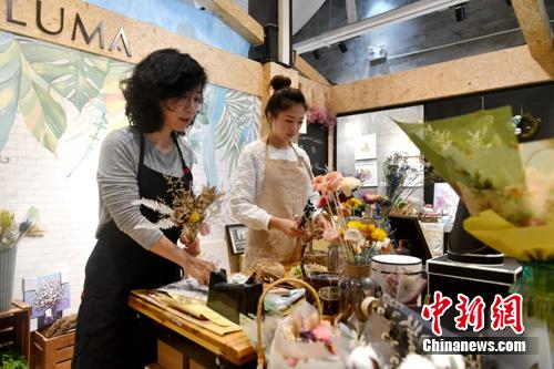 图为李函儒与妈妈在店里制作花束。 吕明 摄