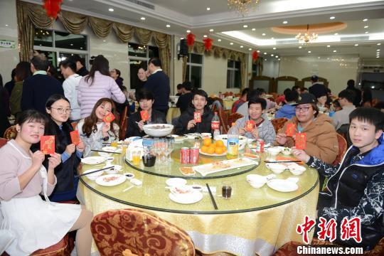 参加年夜饭的华侨大学境外生们展示学校派发的“压岁钱”。　张为健 摄