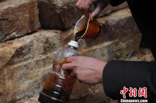 一名村民将不明液体灌入透明饮料瓶内。　　孟梅 摄