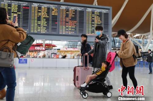 旅客带着孩子前往办票柜台办理登机手续。　殷立勤 摄