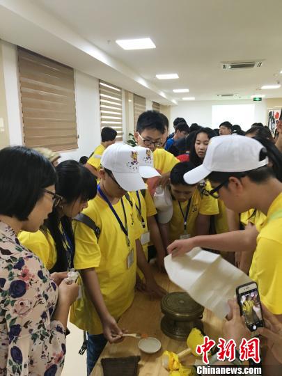 图为华裔青少年当日在广西自治区博物馆人员的指导下尝试拓印一面小的铜鼓。钟建珊 摄