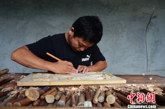 7月11日，记者在王吉波、王吉涛兄弟位于济南兴隆街道的家中看到，在一张摆着近百个雕刻工具的木案前，兄弟俩正在进行进行木雕工作。图为哥哥王吉波进行木雕。　郝学娟 摄