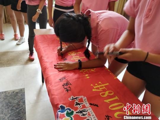 营员朱子慧正在夏令营营旗上一笔一划地签名，因为比较少写汉字，她的字迹稍显幼稚。　林晓丹 摄