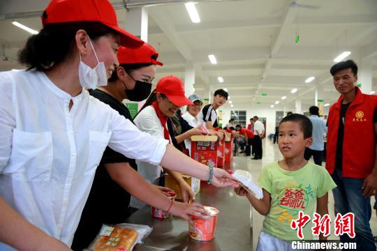 8月24日，志愿者在潍坊寿光市营里镇第二初级中学安置点为灾民发放救援物资。　梁犇 摄