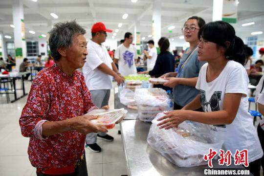 8月24日，志愿者在潍坊寿光市营里镇第二初级中学安置点为灾民发放救援物资。　梁犇 摄