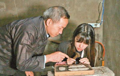 非遗传人吴水根（左）在指导徒弟制作银器。本报记者 史一棋摄