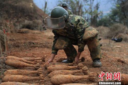 中国人民解放军南部战区陆军云南扫雷大队在雷场扫雷期间，一名战士将一枚搜排出来的炮弹放至临时存放点。　杨萌 摄