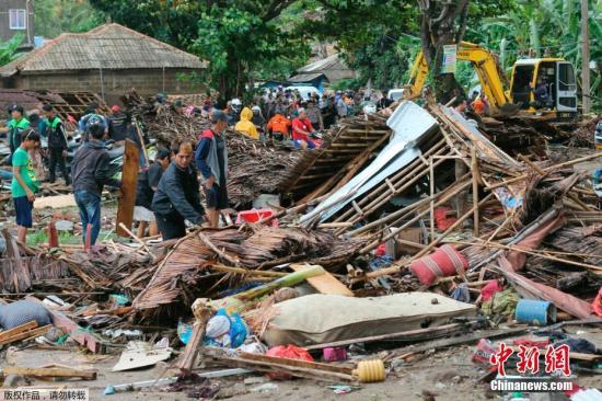 图为印度尼西亚卡里塔的灾民在受海啸破坏的房屋内检查被困者。
