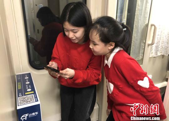 在南昌至北京西的Z66次列车10号车厢自动售货柜前，徐伊然(右一)与姐姐秦玥茗正在通过扫描二维码选购零食。　胡国林 摄