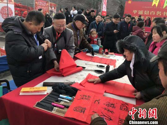 在古城南门内的兴国寺旧址，百名书法家挥笔泼墨，向民众赠送春联。　胡健 摄