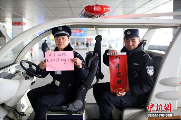 2月1日，随着春节临近，南京铁路公安处南京站派出所的民警在纸上写下“平安春运，有我们护航”、“天下无贼是我们最大的心愿”、“平安归途么么哒”等话语，用别样的方式给旅客们送上温馨的新年祝福。图为南京火车站周边巡逻民警和特勤送出温馨祝福语。中新社记者 泱波 摄