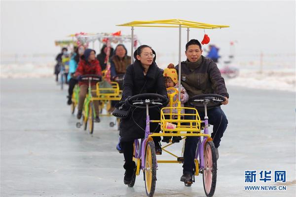 游客在南疆巴音郭楞蒙古自治州境内的博斯腾湖冰面上骑自行车（2月6日摄）。