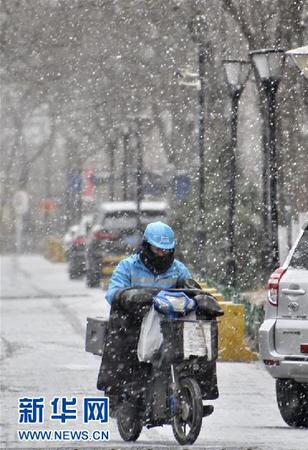 2月12日，在大兴区，一名快递员在雪中骑行。 新华社记者 李欣 摄