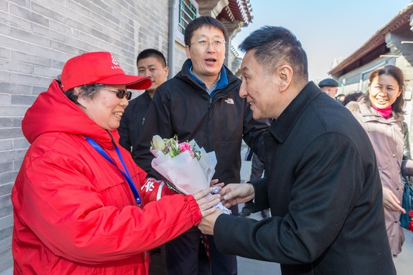 图二：东城区政协副主席毕博闻向正在执勤的守望岗志愿者赠送鲜花