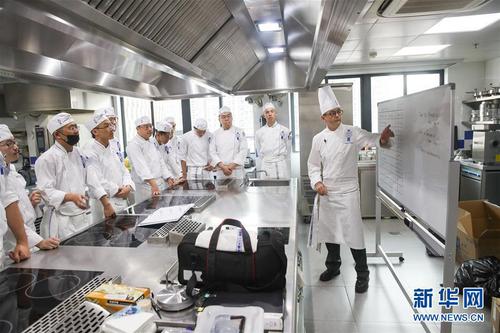 这是2018年10月17日， 来自法国的菲利普（右）在上海蓝带厨艺职业技能培训学校的教室内给学员们教授法式厨艺。 新华社记者 丁汀 摄