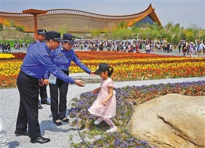 城管劝离进入花坛拍照的游客。北京市城管执法局供图