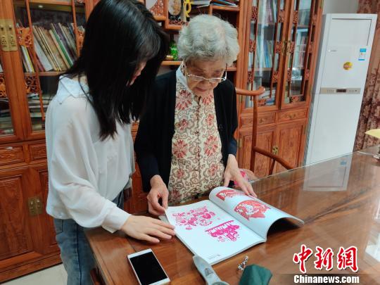 民间剪纸艺术家、国家级非遗传承人袁秀莹向记者介绍她以前创作的作品。叶秋云 摄