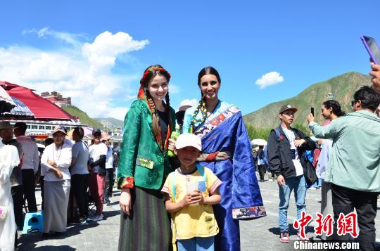 图为身着藏族服装的外籍模特比赛完与当地的小孩合影留念。　鲁丹阳 摄