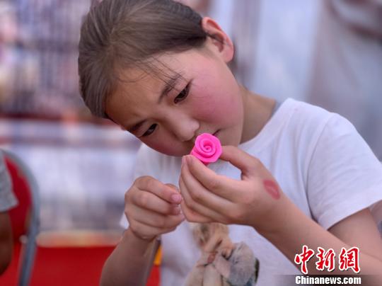 图为小女孩正在用米塑捏玫瑰花。　孙睿 摄
