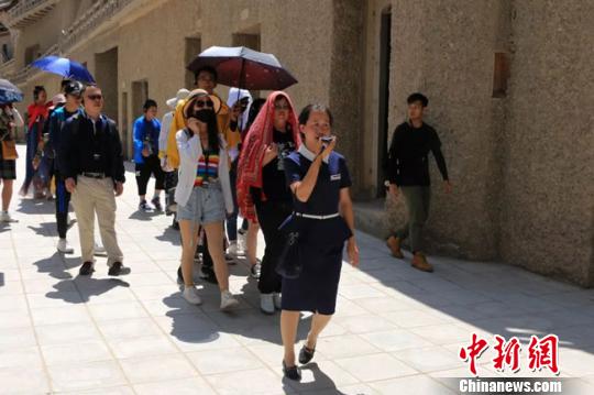 图为敦煌莫高窟志愿者讲解员正在带领游客参观。　敦煌研究院供图 摄