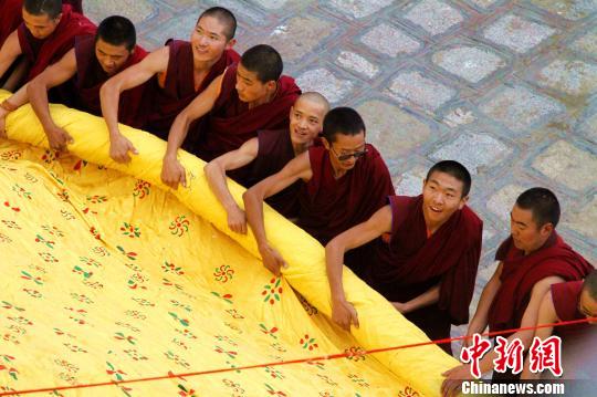 藏语“雪”为酸奶，“顿”意为宴，所以这一节日也被称为“酸奶节”。图为2018年拉萨哲蚌寺僧人合力展开巨幅释迦牟尼佛唐卡。(资料图) 赵朗 摄