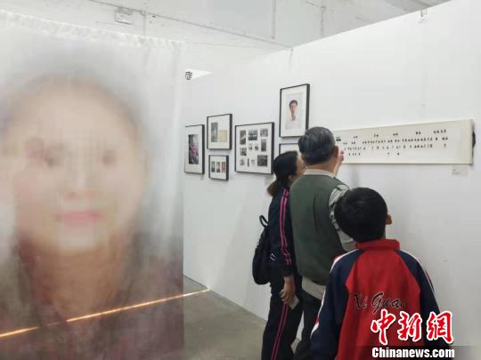 在第19届中国平遥国际摄影大展柴油机展区的一角，一张大幅的人像彩画吸引来往游客驻足拍照。　杨佩佩 摄