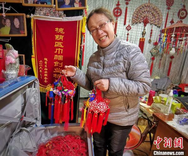 济南结艺非遗传承人胡立华向记者展示自己将带往塞尔维亚庙会活动上的中国结作品。　赵晓 摄