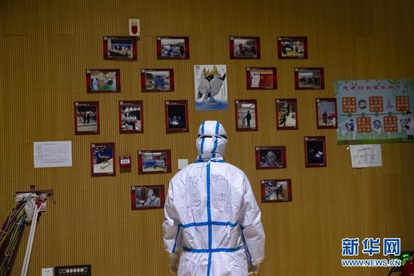3月9日晚，在武汉市洪山体育馆武昌方舱医院，名叫管茜的医务人员查看贴有该方舱里的新冠肺炎患者和医务人员照片的照片墙。 新华社记者 沈伯韩 摄
