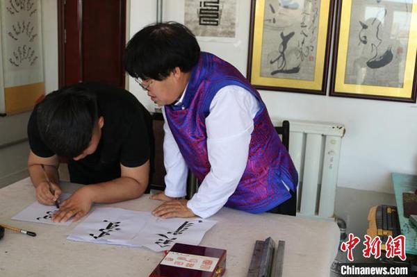 图为那布查指导儿子学习蒙古文书法。　张美娜 摄