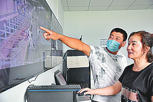 在黑龙江省林甸县众晔牧场，养牛大户吕建华(左)通过监控屏幕查看托养牛的情况。