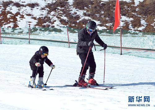 12月27日，在娅豪国际滑雪场内，一名儿童在大人的指导下学习滑雪。