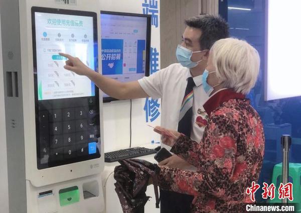 资料图：重庆移动营业员帮助引导老年客户通过自助机充缴话费。供图