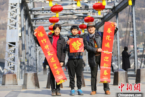 2021年春节期间，台湾夫妻杜书亿和王梅芬带着孩子一起在兰州中山铁桥前合影留念。 中新社记者 高展 摄