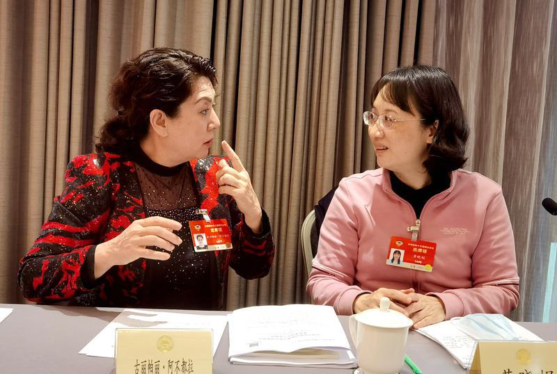 古丽帕丽•阿不都拉委员（左）和黄晓娟委员就提案各抒己见。 特邀委员记者 唐江澎摄