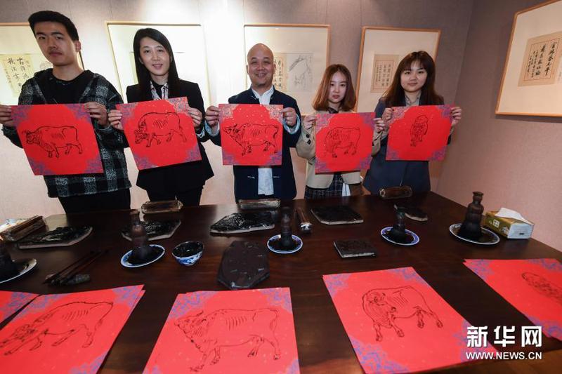 3月16日，在浙江理工大学丝绸博物馆内，国家级非遗项目木版水印技艺代表性传承人魏立中（中）与师生展示刚印制的木版水印作品。新华社记者 徐昱 摄