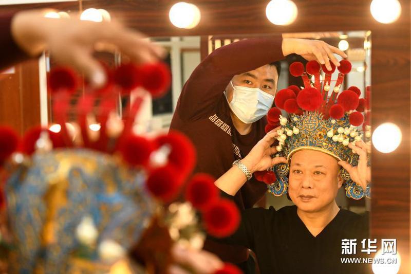 3月16日，戏曲盔头制作维修师朱宝辉（左）在河北省石家庄大剧院后台为演员试戴盔头。