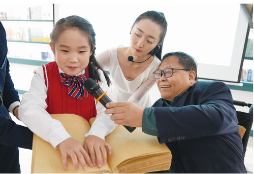 中国残联副主席吕世明（右一）与视障小朋友陈禹心向嘉宾展示盲文书籍王鹏 摄