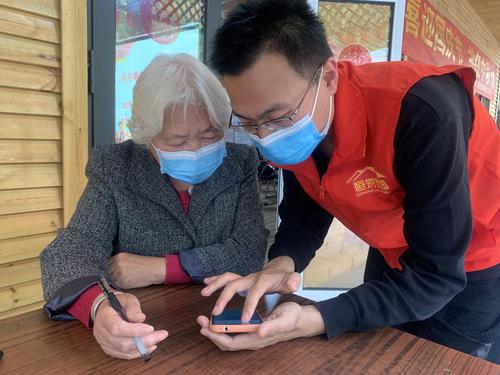 河北石家庄恒爱家园社工服务中心社工张义德指导社区老人使用智能手机。