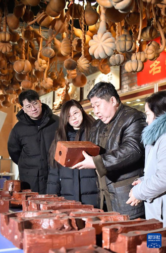 赵伟（右二）向徒弟们介绍天津葫芦制作技艺使用的瓦模（2月10日摄）。 新华社记者 孙凡越 摄