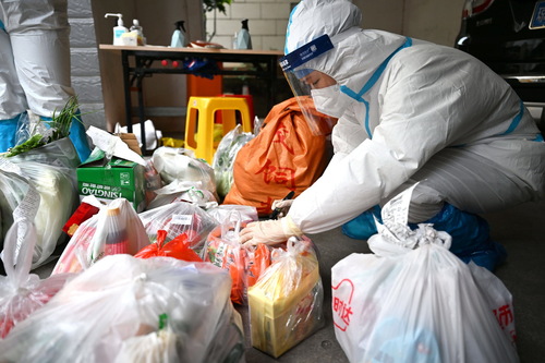 4月4日，在海口市琼山区一个封控居民小区内，志愿者为居民搬运生活物资。