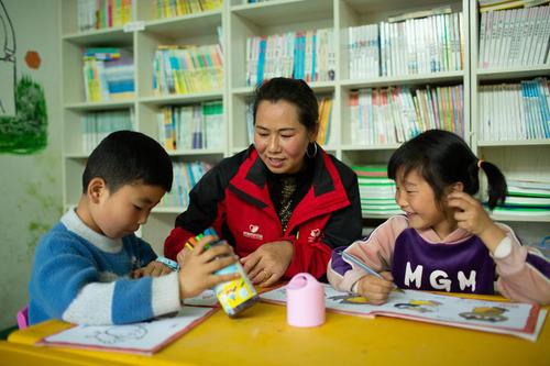 贵州省毕节市七星关区的“童伴妈妈”许世琴在“童伴之家”带孩子们做作业、阅读、学手工，开展多样化服务。胜春 摄