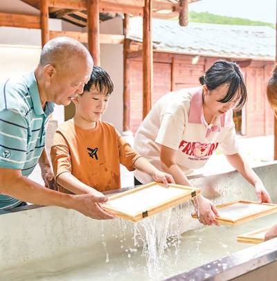 游客在福建泉州一家古法造纸技艺馆体验捞纸。