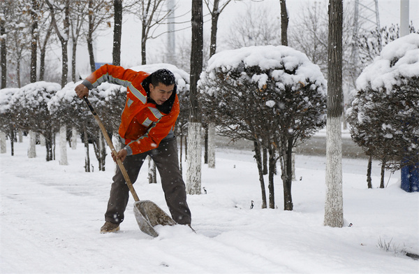环卫工人在乌鲁木齐经开区（头屯河区）紫阳湖中路清扫人行道上的积雪。谢龙 摄