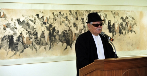 5月3日，李奇茂教授在交流展开幕式上发言，身后是他的画作《万蹄飞黄沙》。
