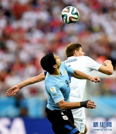 6月19日，乌拉圭队球员路•苏亚雷斯（前）与对方球员争顶。